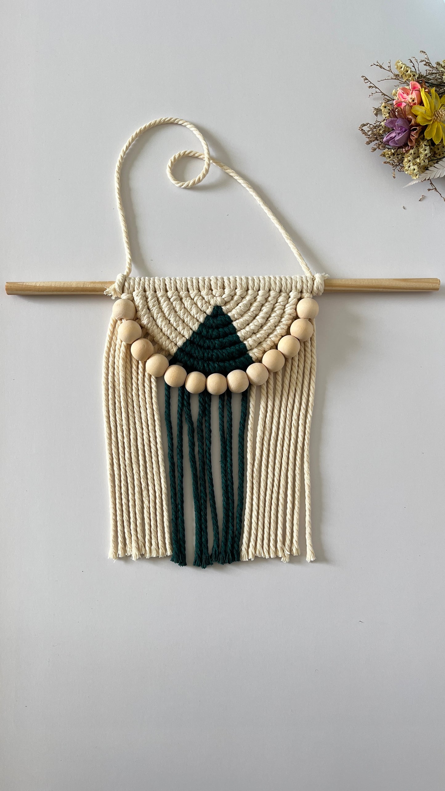 Macrame wall hanging with geometric design on a plain background